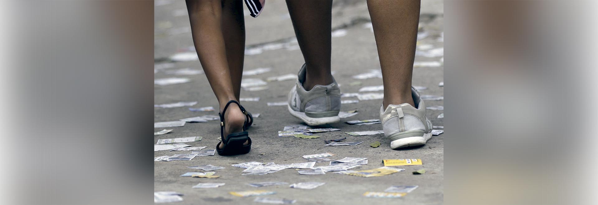 Pedestres passam em calçada com folhetos de propaganda política no primeiro turno das eleições de 2023, no bairro da Tijuca, no Rio de Janeiro