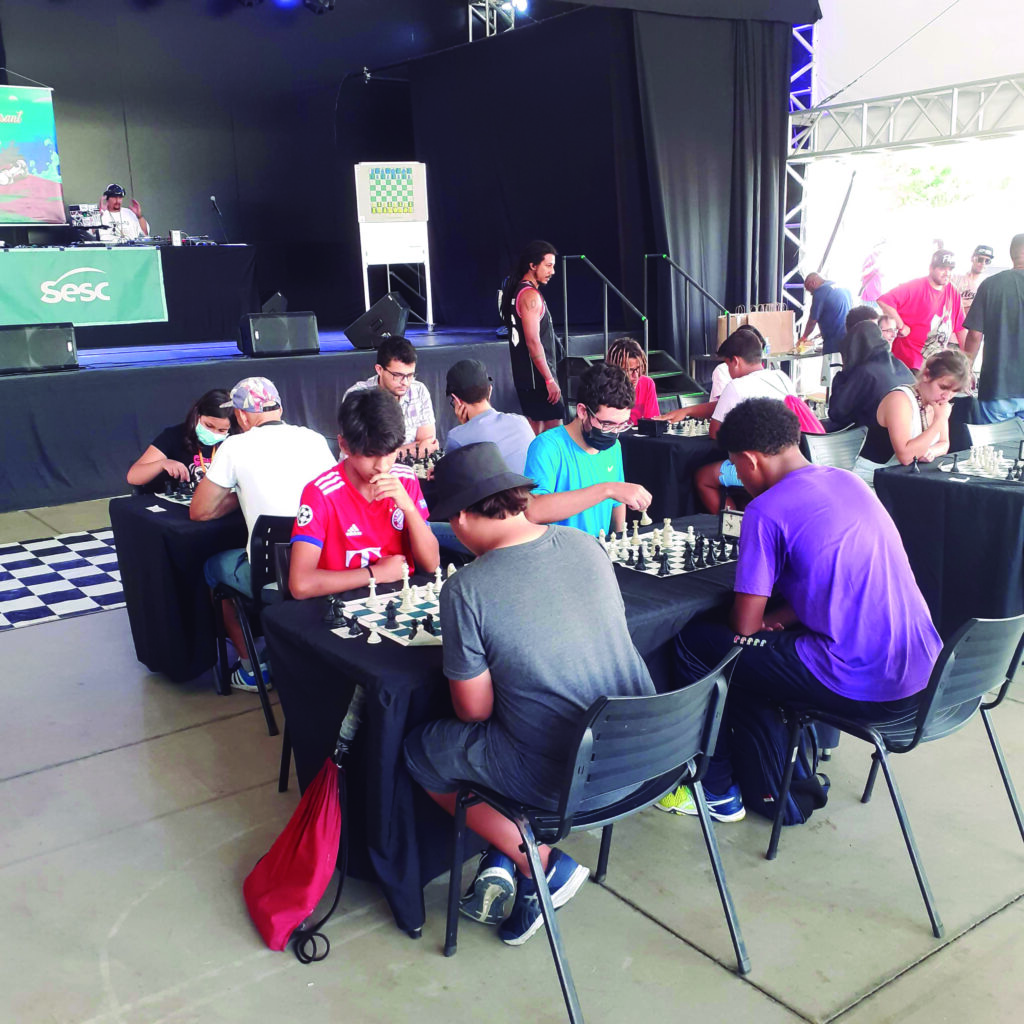 Um grupo de pessoas sentadas ao redor de uma mesa jogando xadrez