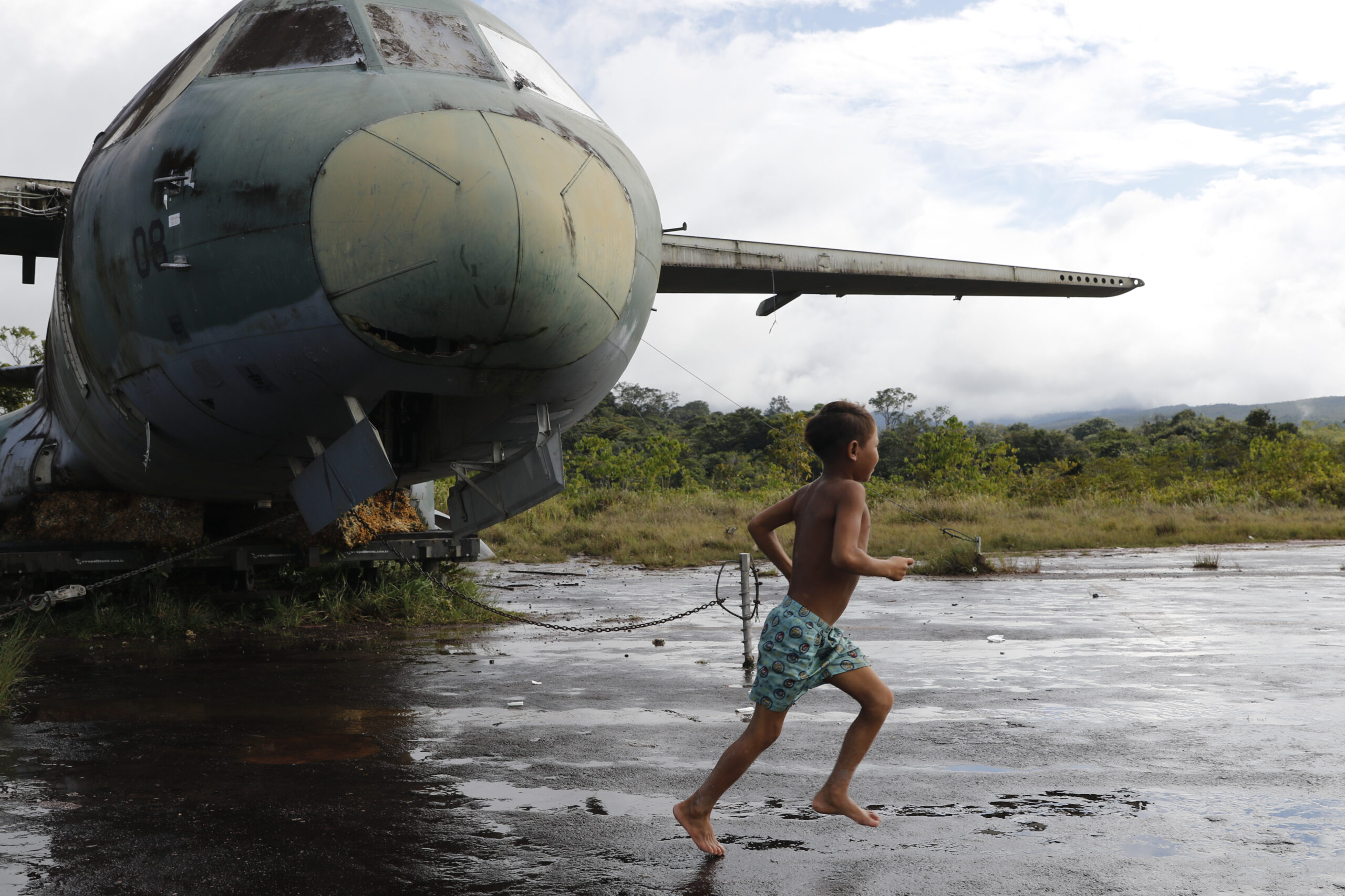 Criança Yanomami brinca ao lado de sucata de avião da FAB no aeroporto de Surucucu, em Roraima: militares pediram verba para atuar na região apesar de orçamento bilionário (Foto: Fernando Frazão/Agência Brasil) 